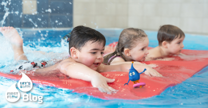 Drei Kinder lieger auf einer Schwimmmatte im Wasser während eines Babyschwimm- oder Kinderschwimmkurses.