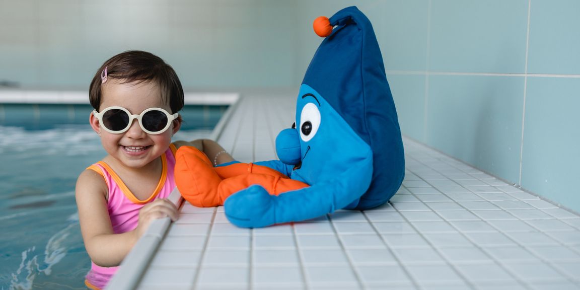 Kind mit Sonnenbrille im Wasser bei der Safe & Sunny Kampagne