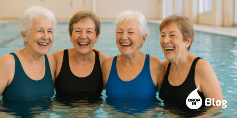 Vier fröhliche Seniorinnen sitzen im Schwimmbadrand und lachen zusammen.